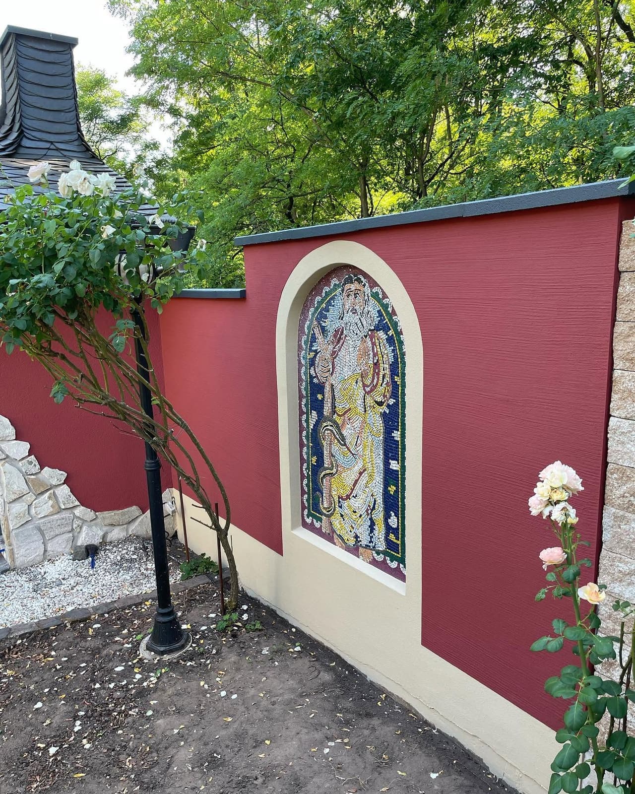 Fertig gestrichene rote Gartenmauer mit Mosaik