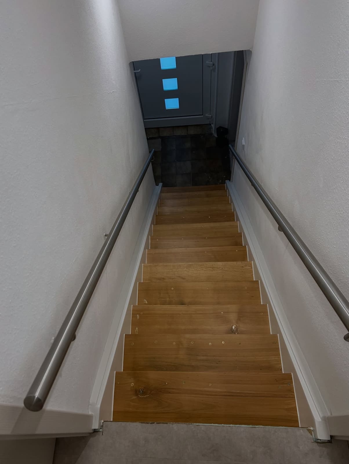 Treppenaufgang mit grau gestrichenen Wänden und Holzstufen